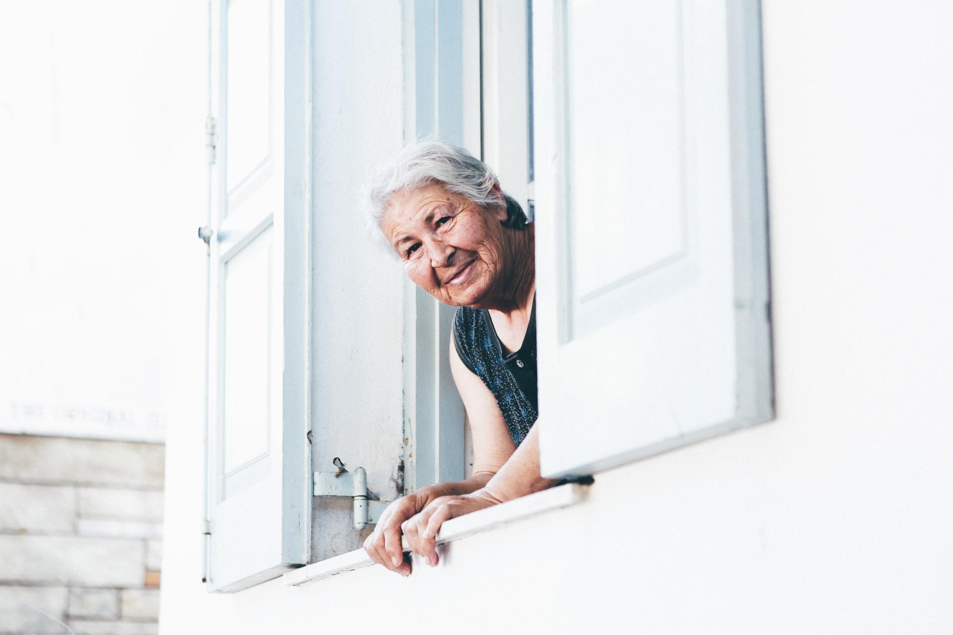 Bild von einer älteren Dame, die aus dem Fenster schaut